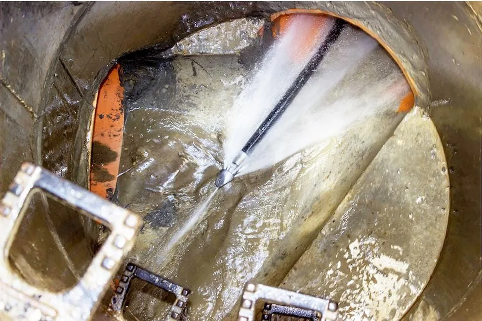 Vic's Plumbing high-pressure water jetting clearing a drain line inside a manhole