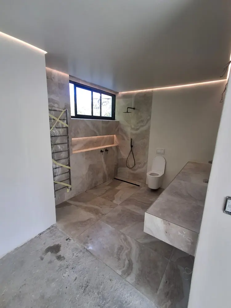 New main bathroom fit-out with a walk-in shower, concealed linear drain, wall-hung WC and stone-tiled finishes