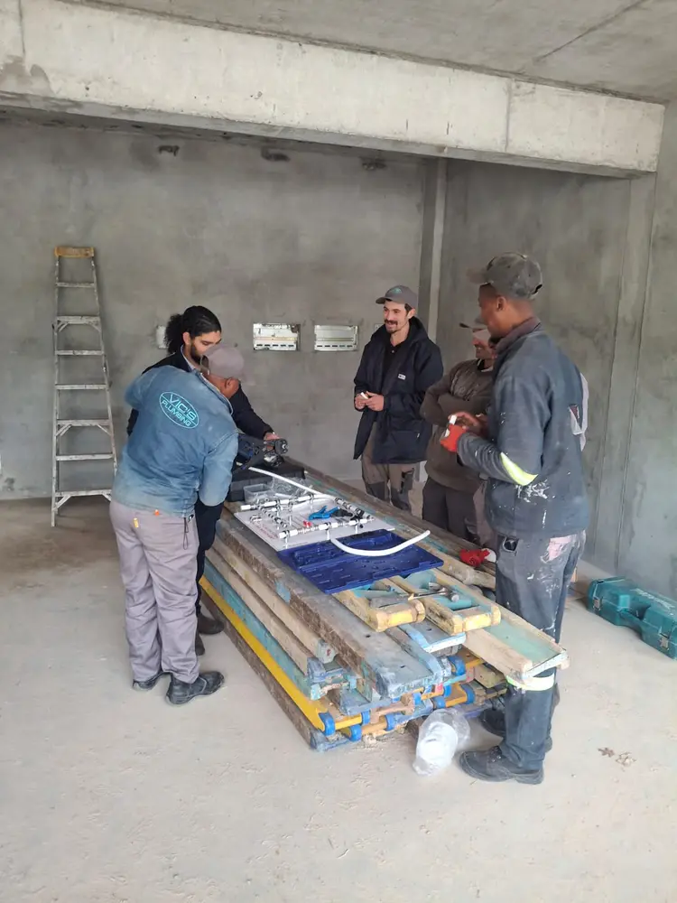 The Vic's Plumbing team assembling a press-fit manifold on a new-build site
